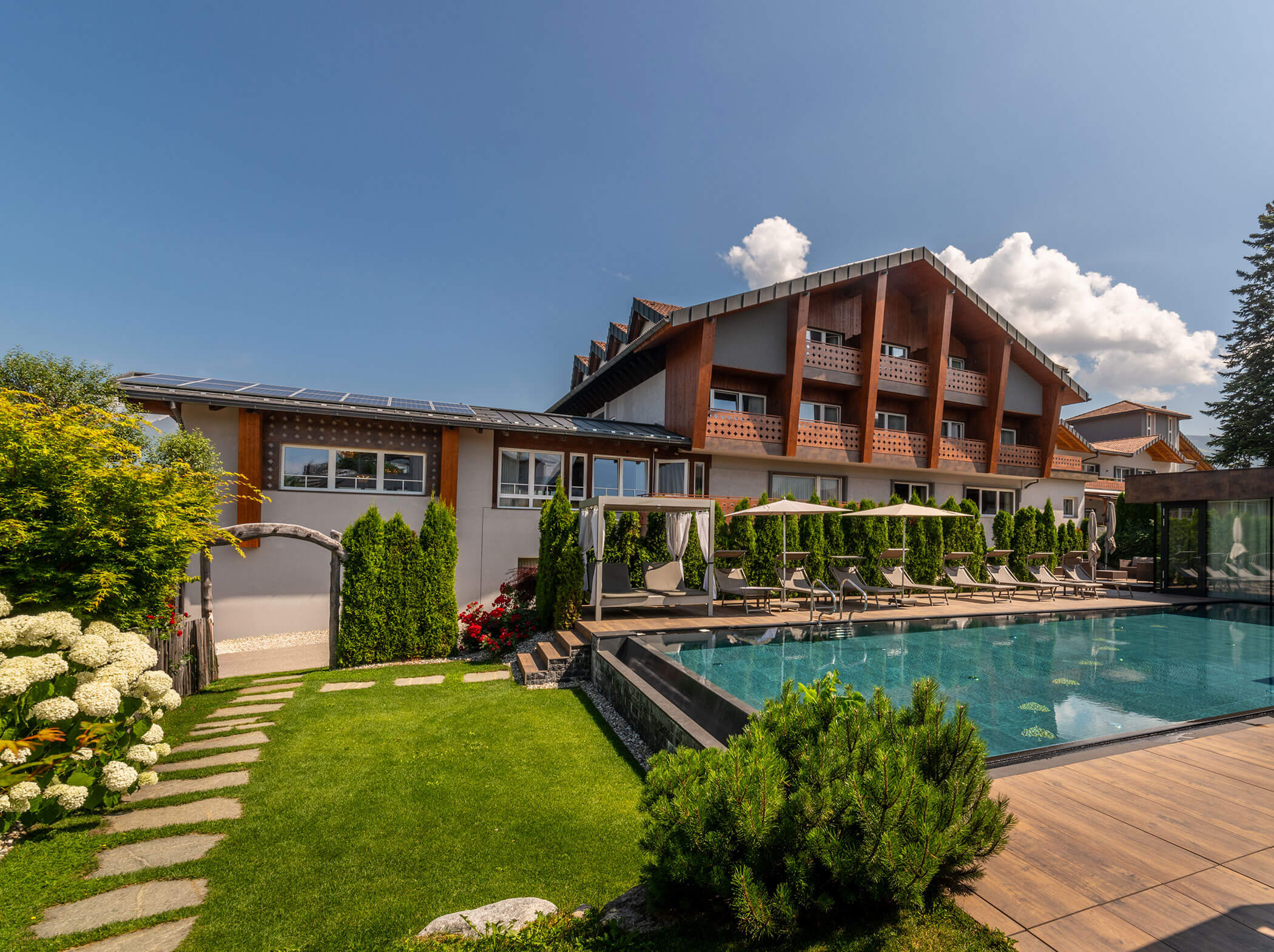 Moderno edificio alberghiero con balconi, piscina all'aperto, lettini e giardino paesaggistico sotto un cielo soleggiato. - Hotel Sun