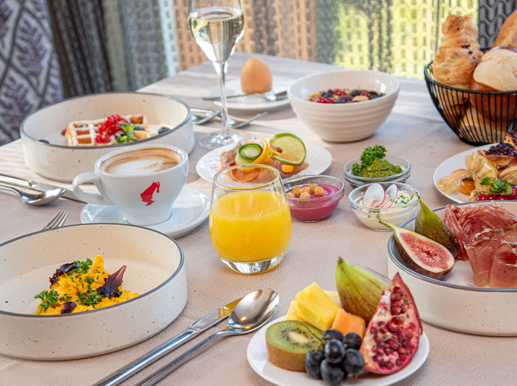 Ein Frühstückstisch mit Obst, Gebäck, Rührei, Kaffee, Saft und verschiedenen Beilagen. - Hotel Sun