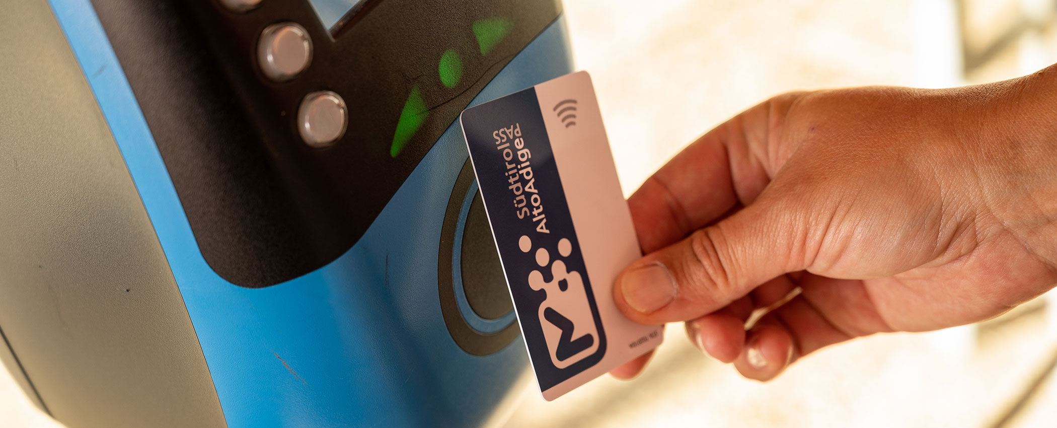 Eine Hand hält eine kontaktlose Karte in die Nähe eines blauen elektronischen Lesegeräts zum Scannen oder Bezahlen. - Hotel Sun