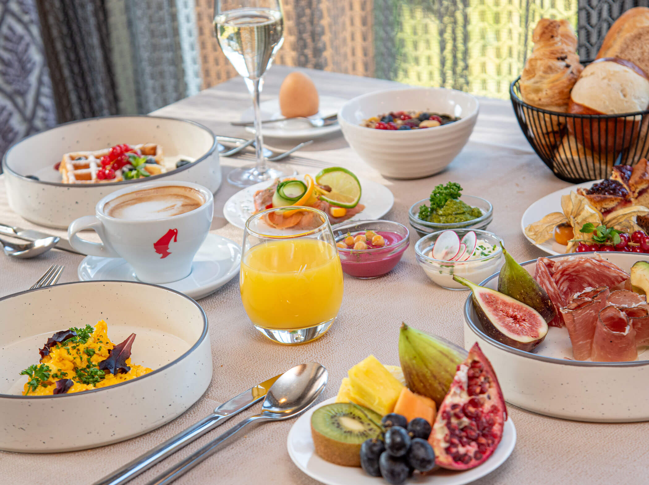 Ein gedeckter Tisch mit verschiedenen Frühstücksprodukten, Obst, Saft, Kaffee, Gebäck und Sekt. - Hotel Sun