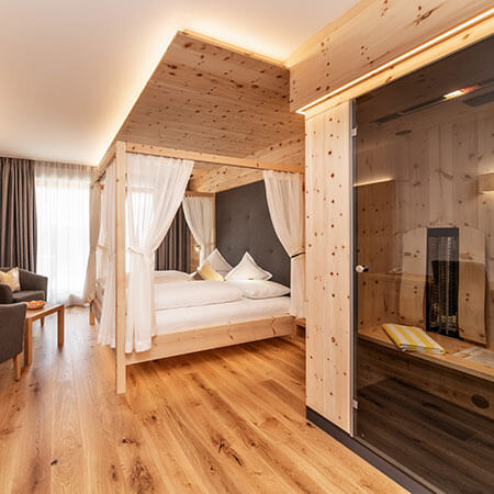 Modernes Hotelzimmer mit Holzakzenten, einem Himmelbett mit weißen Vorhängen und einer Sauna mit Glasabdeckung. - Hotel Sun