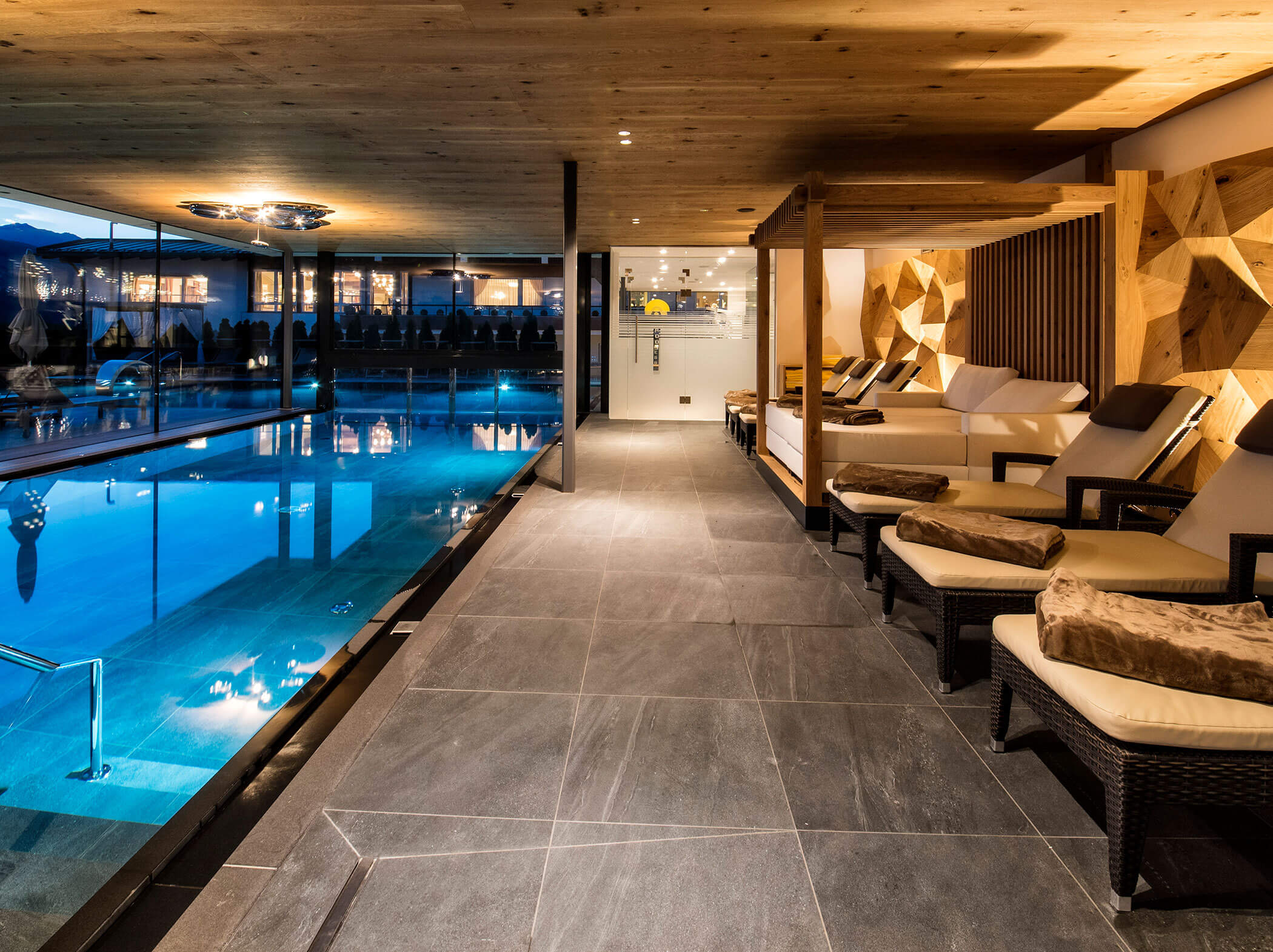 Innenpoolbereich mit Liegestühlen, Holzdecke und gedämpfter Beleuchtung für eine entspannte Atmosphäre. - Hotel Sun
