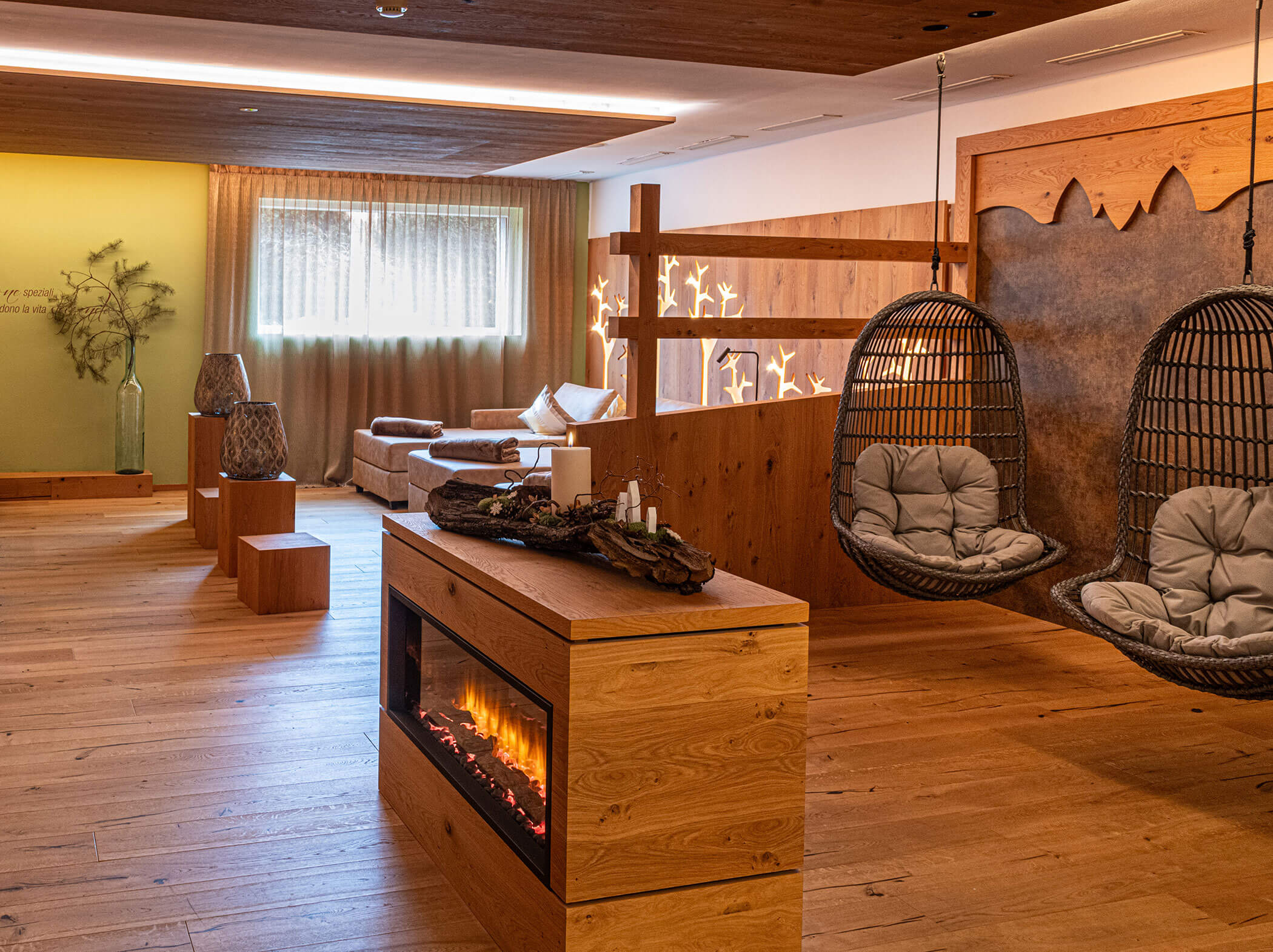 Cozy lounge with hanging chairs, fireplace, and natural wood décor in a sunlit, tranquil room. - Hotel Sun