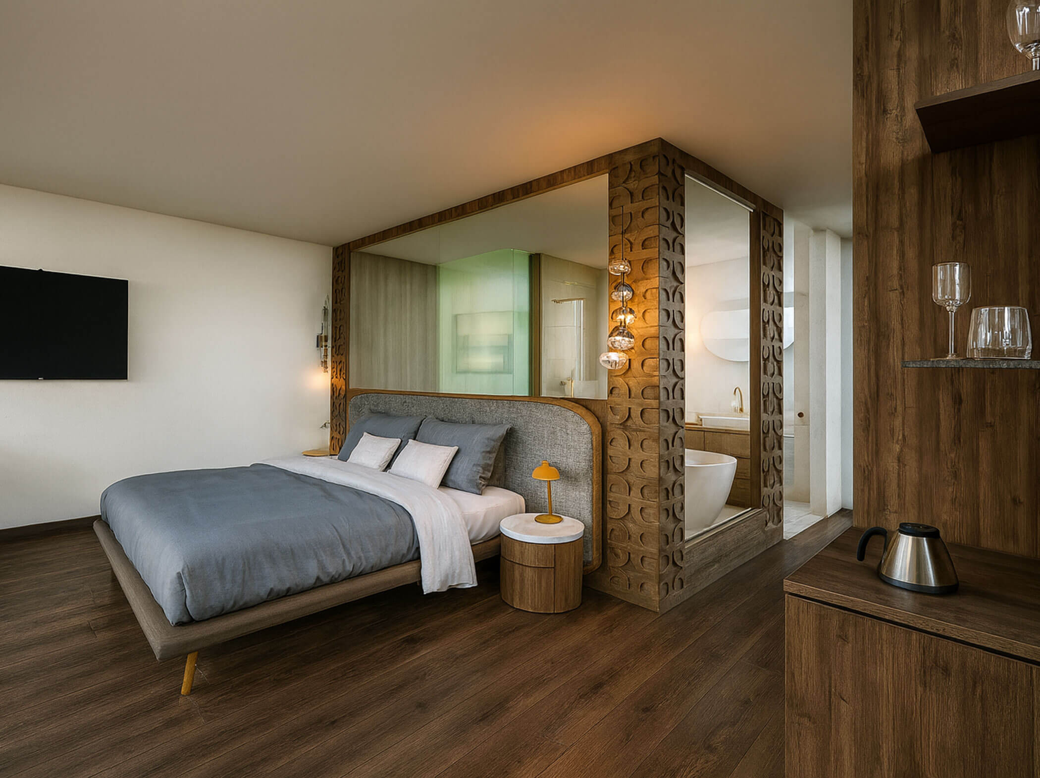 Modernes Hotelzimmer mit einem Doppelbett, Holzfußboden, TV und einer stilvollen Trennwand neben der Badewanne. - Hotel Sun